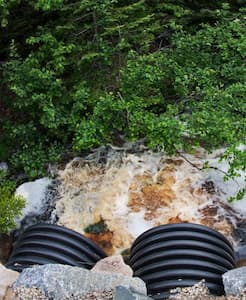 Polluted water discharging from pipes into a natural stream, highlighting runoff issues.