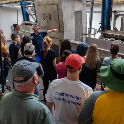 Alumni touring a water treatment plant, highlighting "healthy water, healthy people".