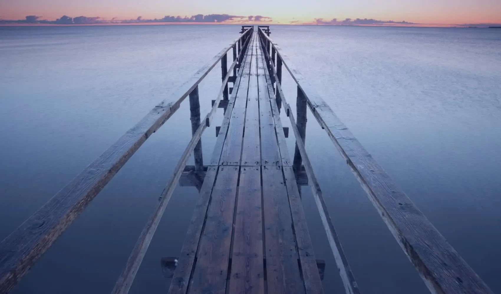 Wooden pier stretching into Lake Winnipeg under a twilight sky.