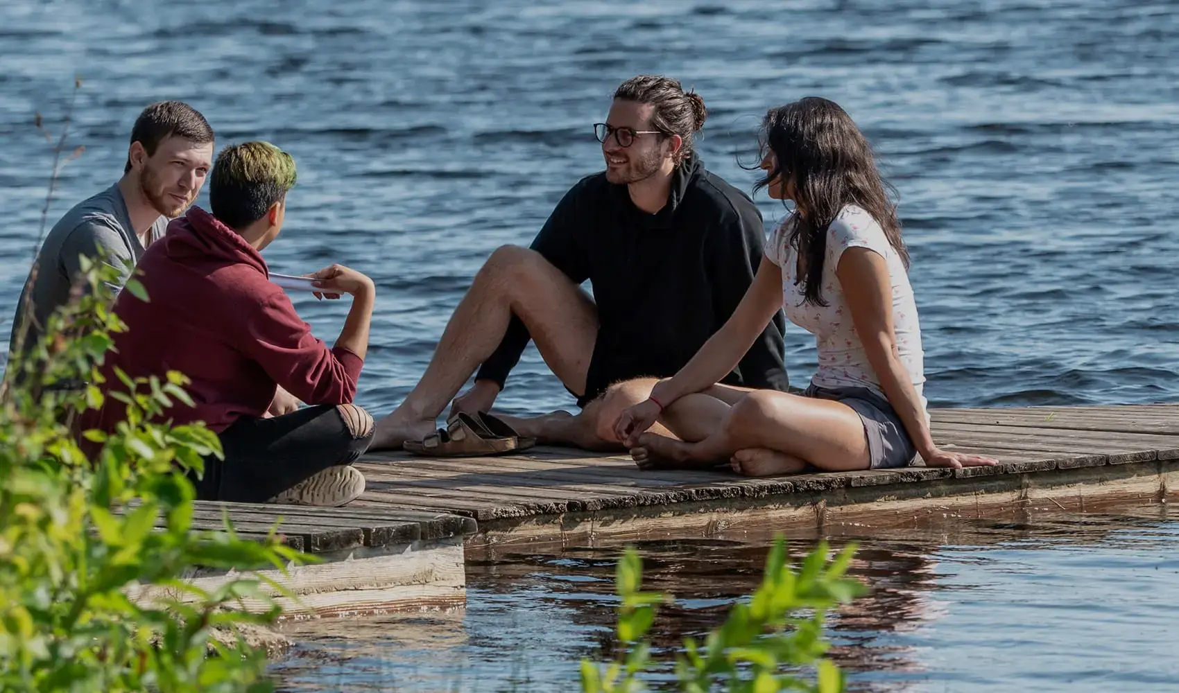 Friends enjoying a relaxed chat on a sunny dock.