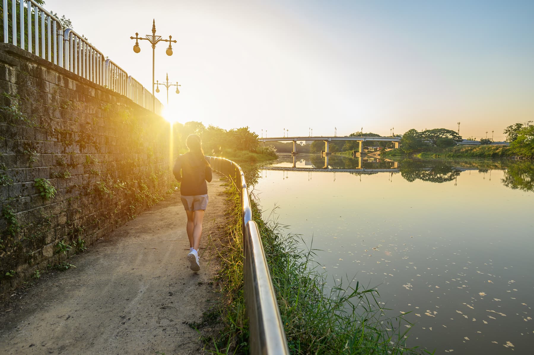 Back view of young fitness woman running at the waterfront