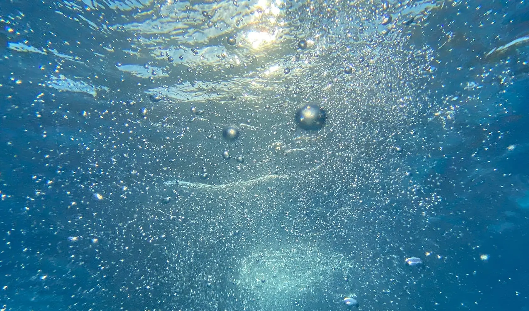Sunlight filtering through water with bubbles, creating a serene underwater scene.
