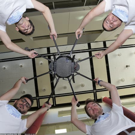 Four AquaEntrepreneur members in matching t-shirts holding up a drone-like device, symbolizing innovation, technology, and entrepreneurial solutions for water-related challenges.