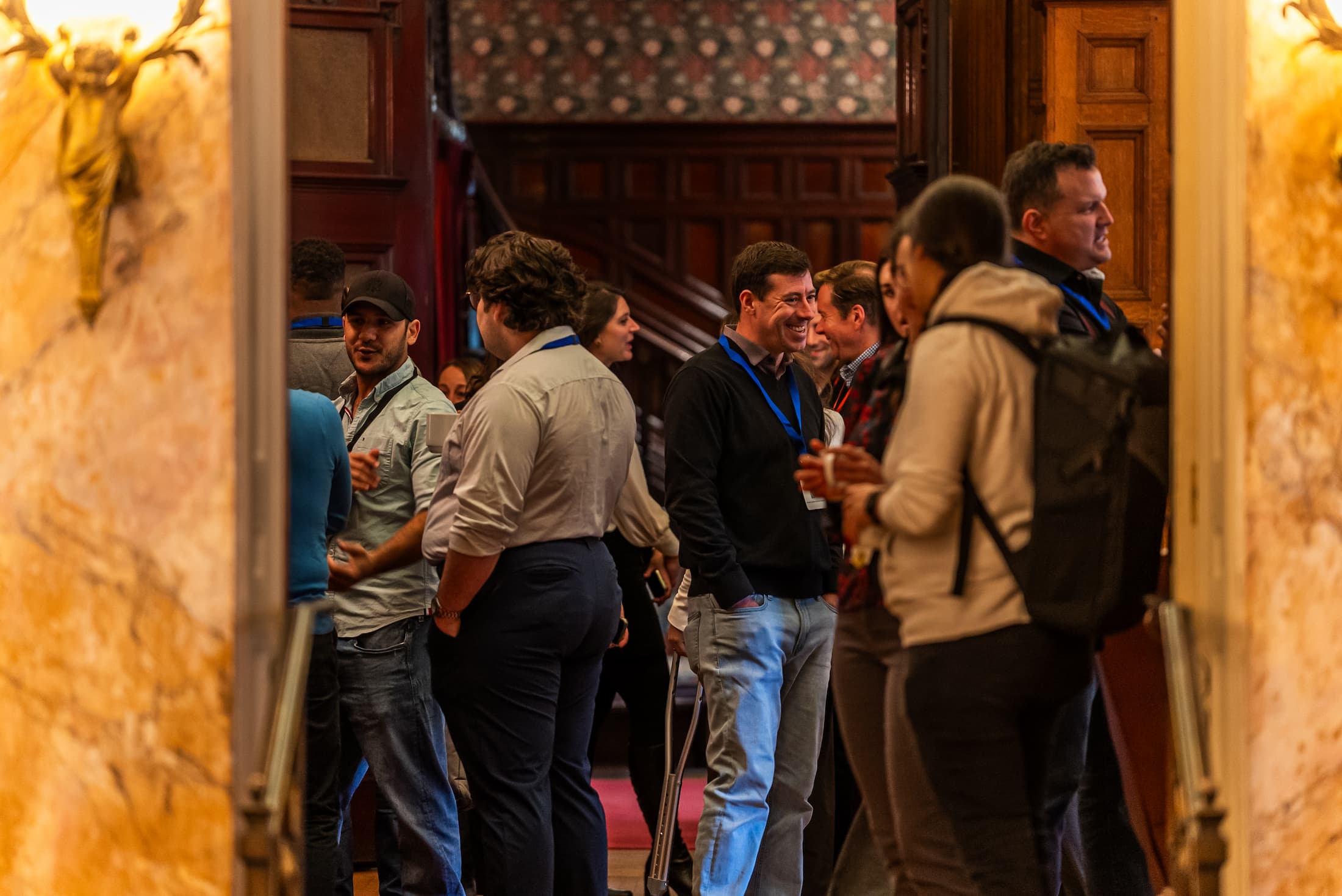 Group of professionals networking and conversing at a conference or business event, wearing name badges in a warmly lit venue. Group of professionals networking and conversing at a conference or business event, wearing name badges in a warmly lit venue.
