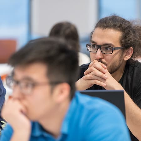 A group of young individuals attentively listening during a workshop or educational session, illustrating focus, curiosity, and critical thinking.